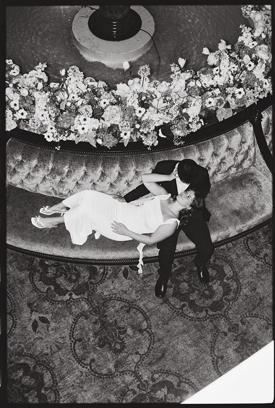 Juan David leaning over Hannah beside the fountain, in black and white