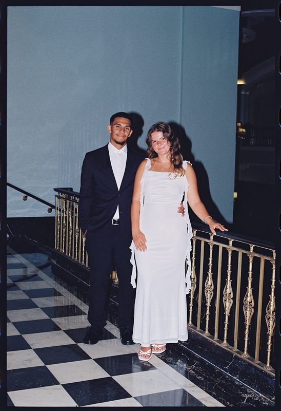 Juan David and Hannah at a brass railing above a checkerboard floor