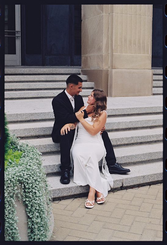 Juan David touching Hannah's face as they sit together on stone steps