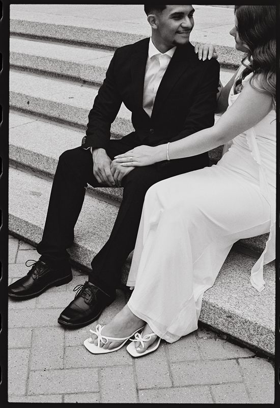 Juan David and Hannah seated on stone steps, her hand on his shoulder, in black and white