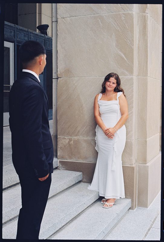 Juan David looking toward Hannah as she leans against a stone column, smiling