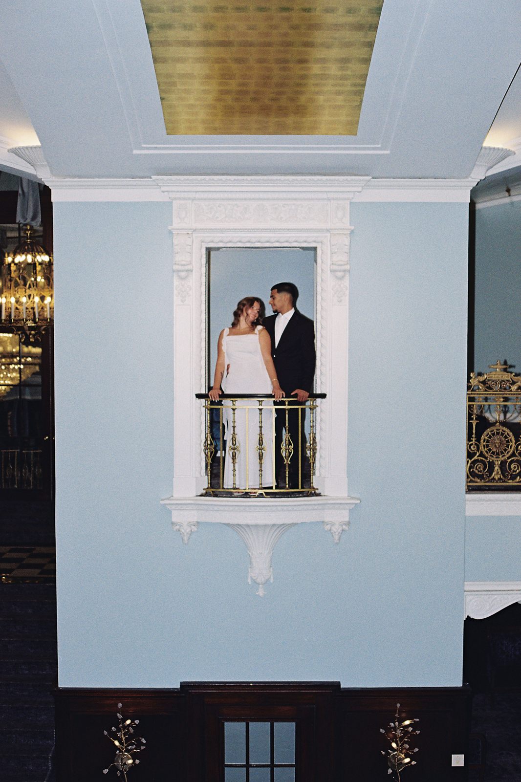 Juan David and Hannah kissing on a small balcony set into a pale blue wall