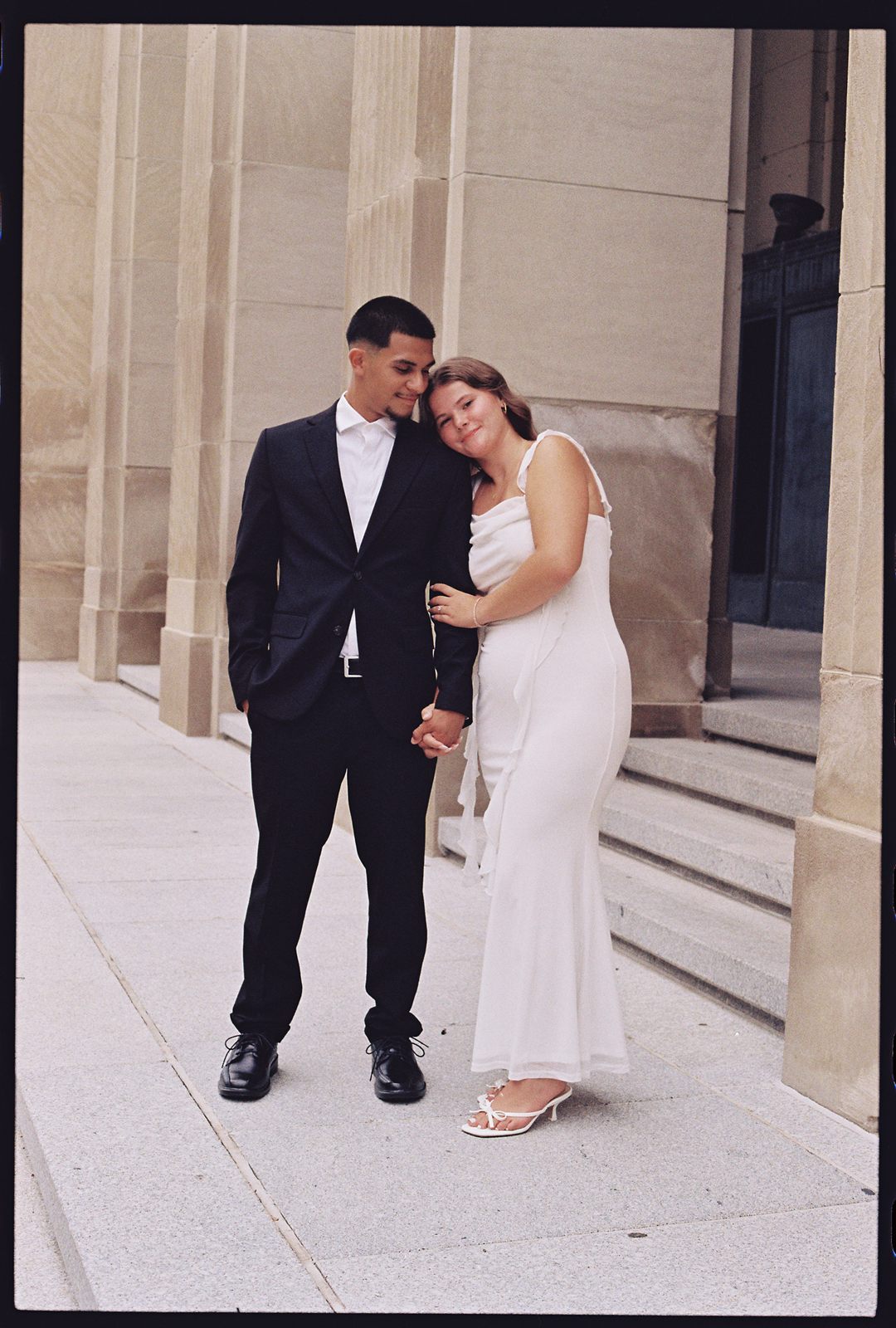 Hannah resting her head on Juan David's shoulder in front of stone columns